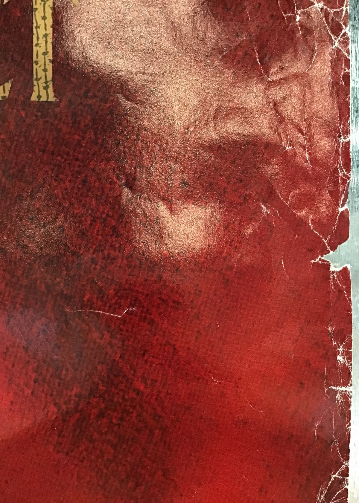 A close-up of a textured red surface with a vertical metallic silver edge and a small gold decorative element at the top left.