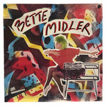 A square wall art print featuring a colorful collage-style illustration with the text 'BETTE MIDLER' across the top, showing a seated figure, abstract shapes, and bold red, yellow, black, blue, and white tones.