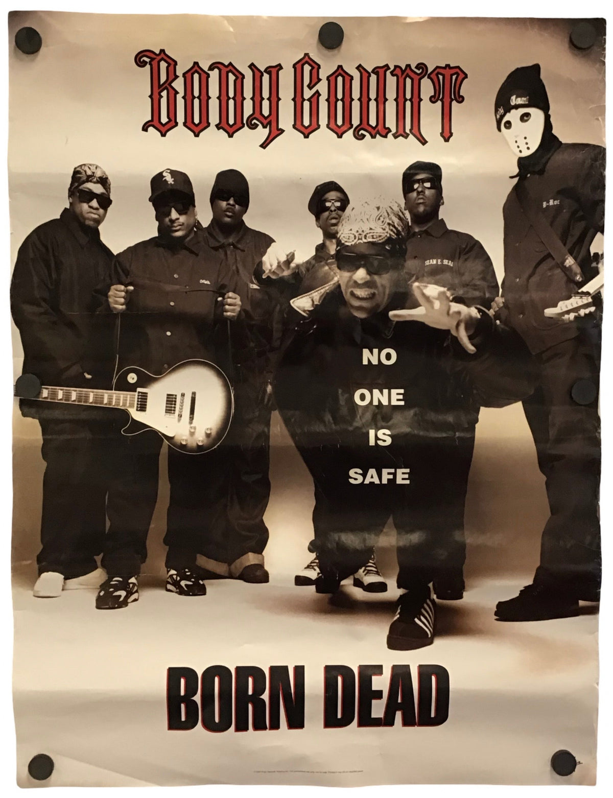 A printed poster or banner featuring the band Body Count with the text 'Body Count' at the top and 'Born Dead' at the bottom. The central printed photo shows several masked figures in dark clothing, with one kneeling figure in the middle wearing a shirt that reads 'NO ONE IS SAFE'.