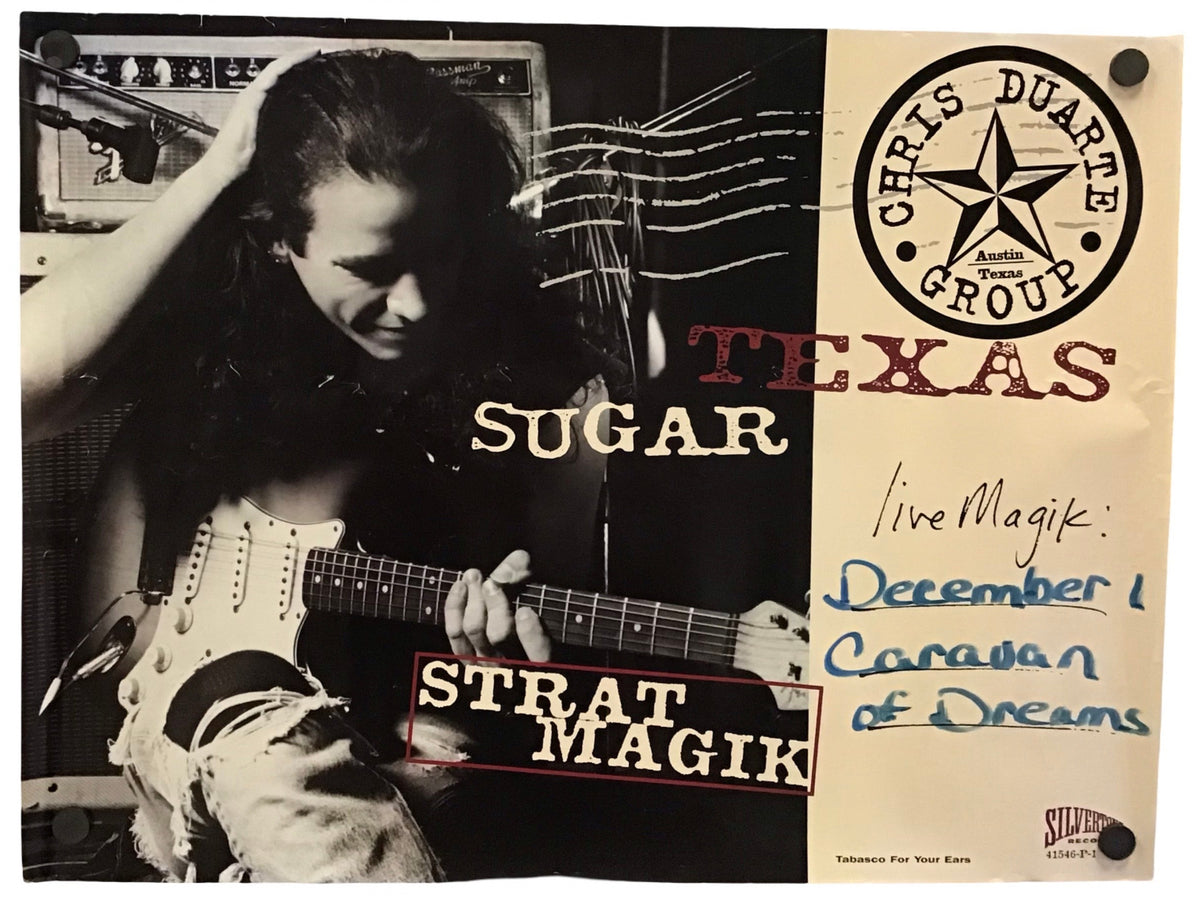 A signed collectible poster of Chris Duarte Group's 'Strat Magik' album featuring a black and white photo of Chris Duarte playing an electric guitar, alongside a beige section with handwritten blue ink writing and a circular 'Chris Duarte Group' logo.