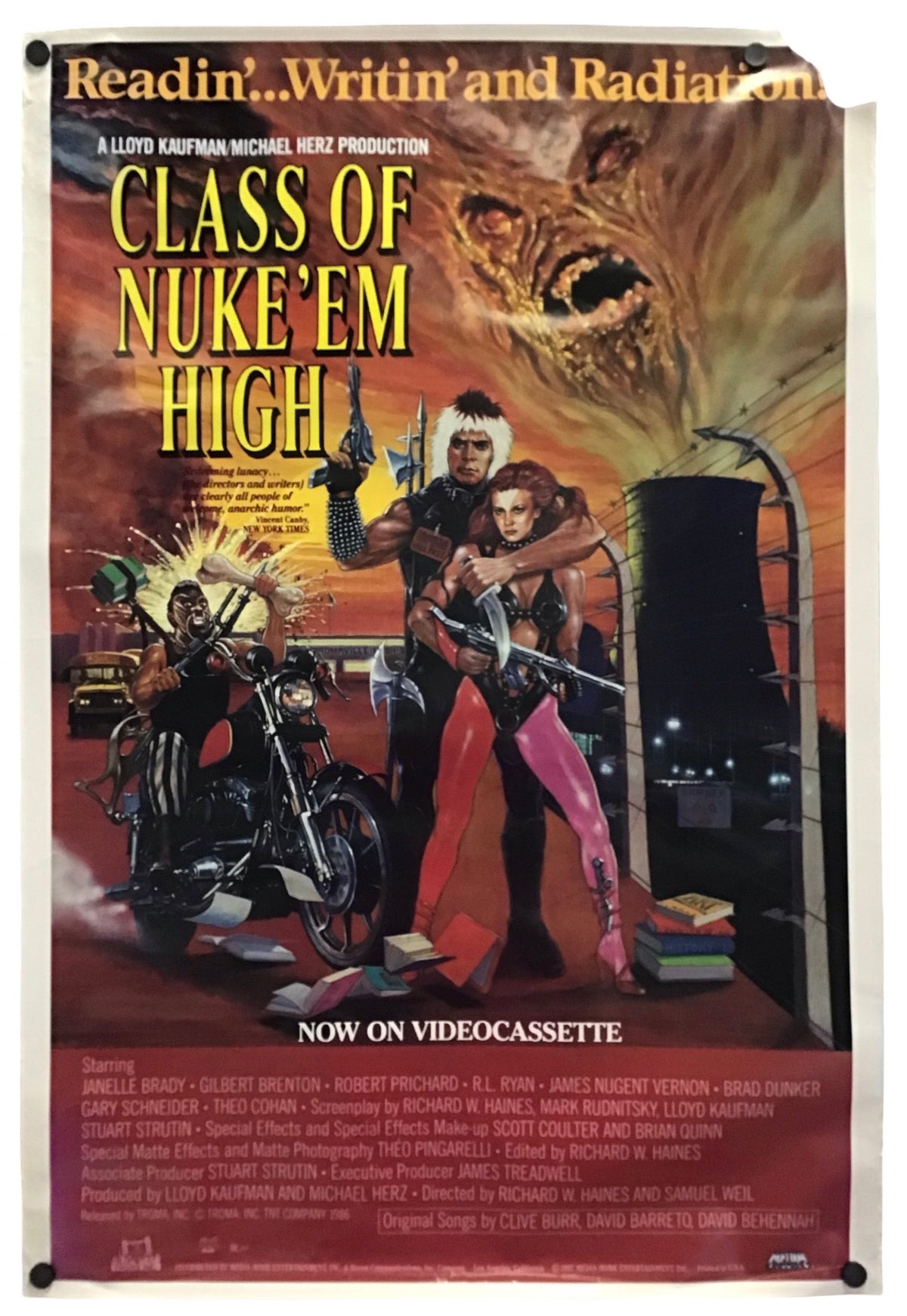 A vintage movie poster for the 1974 film 'Class of Nuke 'em High' featuring a dramatic illustrated scene with a woman in pink pants, a man holding a gun, a motorcycle, and a monster face in the sky. The poster is shown hanging against a white wall with visible tape at the top and bottom corners.