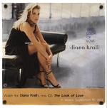 A square printed cover or poster featuring a seated blonde woman in a black dress and heels on a dark chair, with the text 'diana krall', 'The Look of Love', and release details at the bottom. The item is photographed against a plain white background.