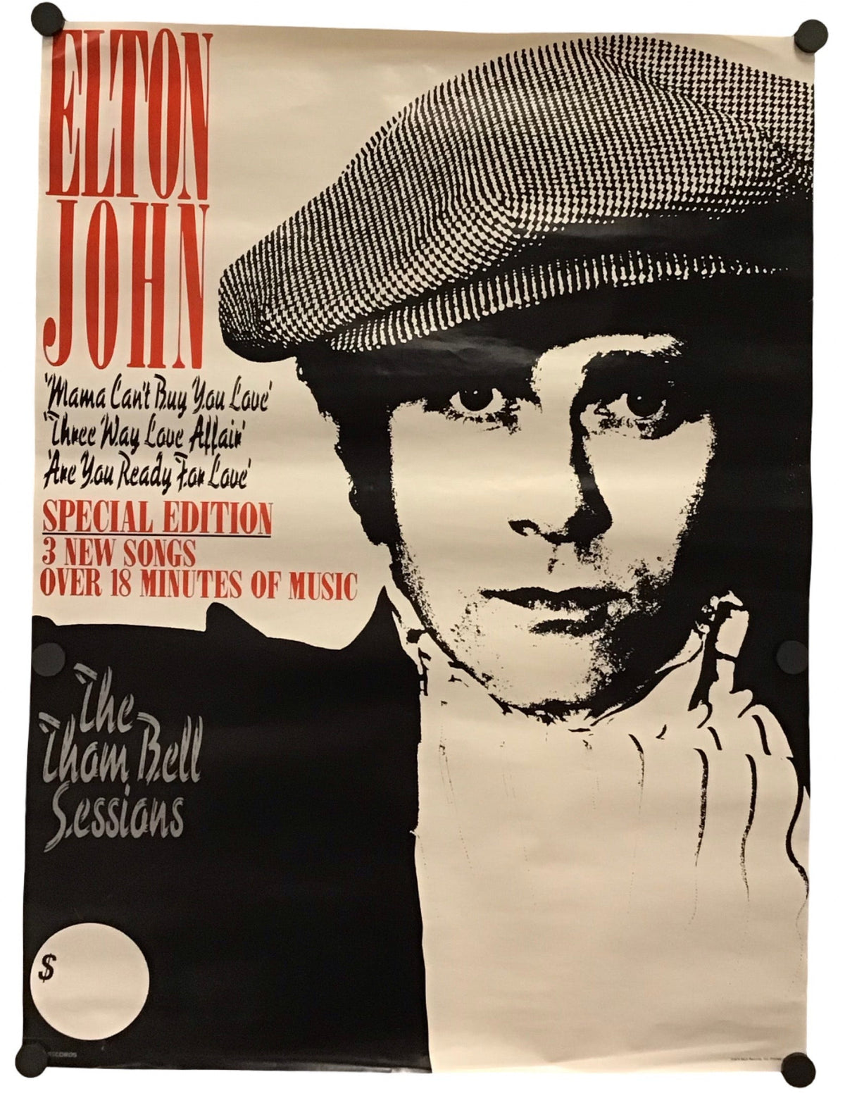 A vintage-style Elton John poster print hanging against a white wall, with black binder clips at the corners. The poster features a large black-and-white portrait of Elton John wearing a flat cap, with red and black text including 'ELTON JOHN' and 'The Zion Bell Sessions.
