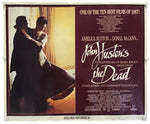 A vintage movie poster for 'John Huston's The Dead' hangs against a white wall, secured with small clips at the corners. The poster features a split design: a warm-toned photograph on the left showing a couple embracing, and a dark reddish-brown text panel on the right with white title lettering and film details.