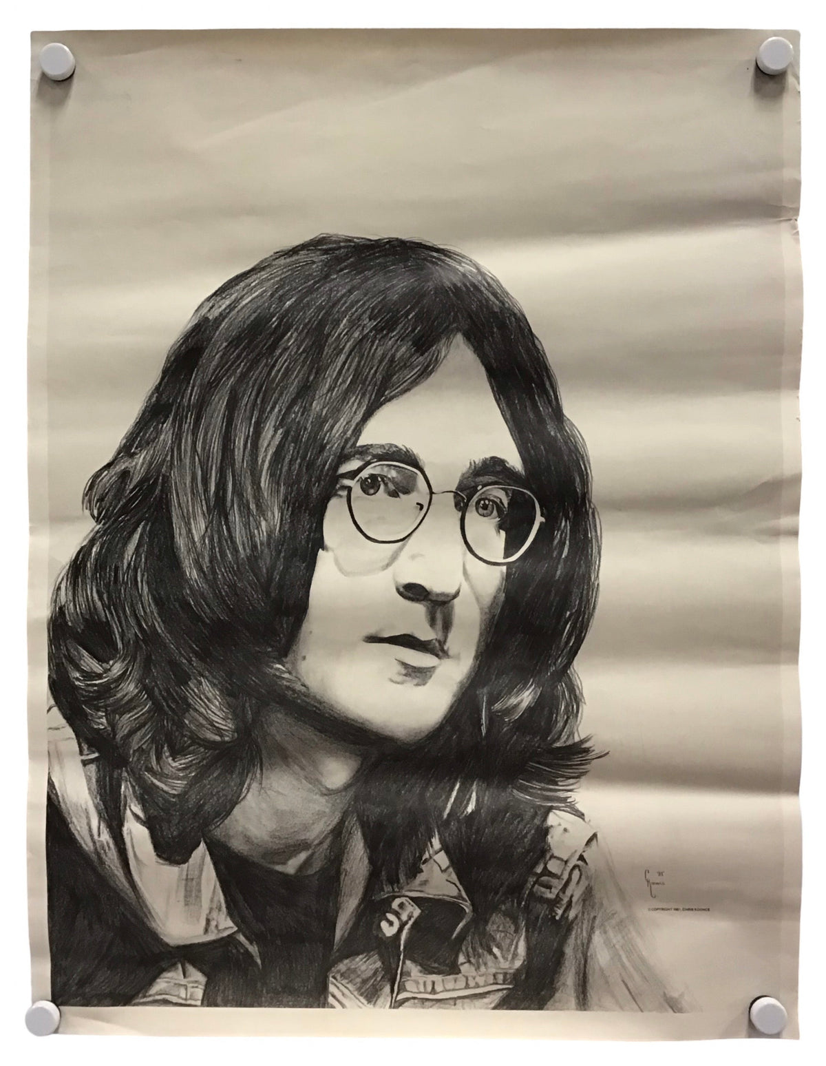 A black and white pencil-style portrait print of John Lennon, displayed on a beige sheet of paper with four binder clips at the corners against a white background.