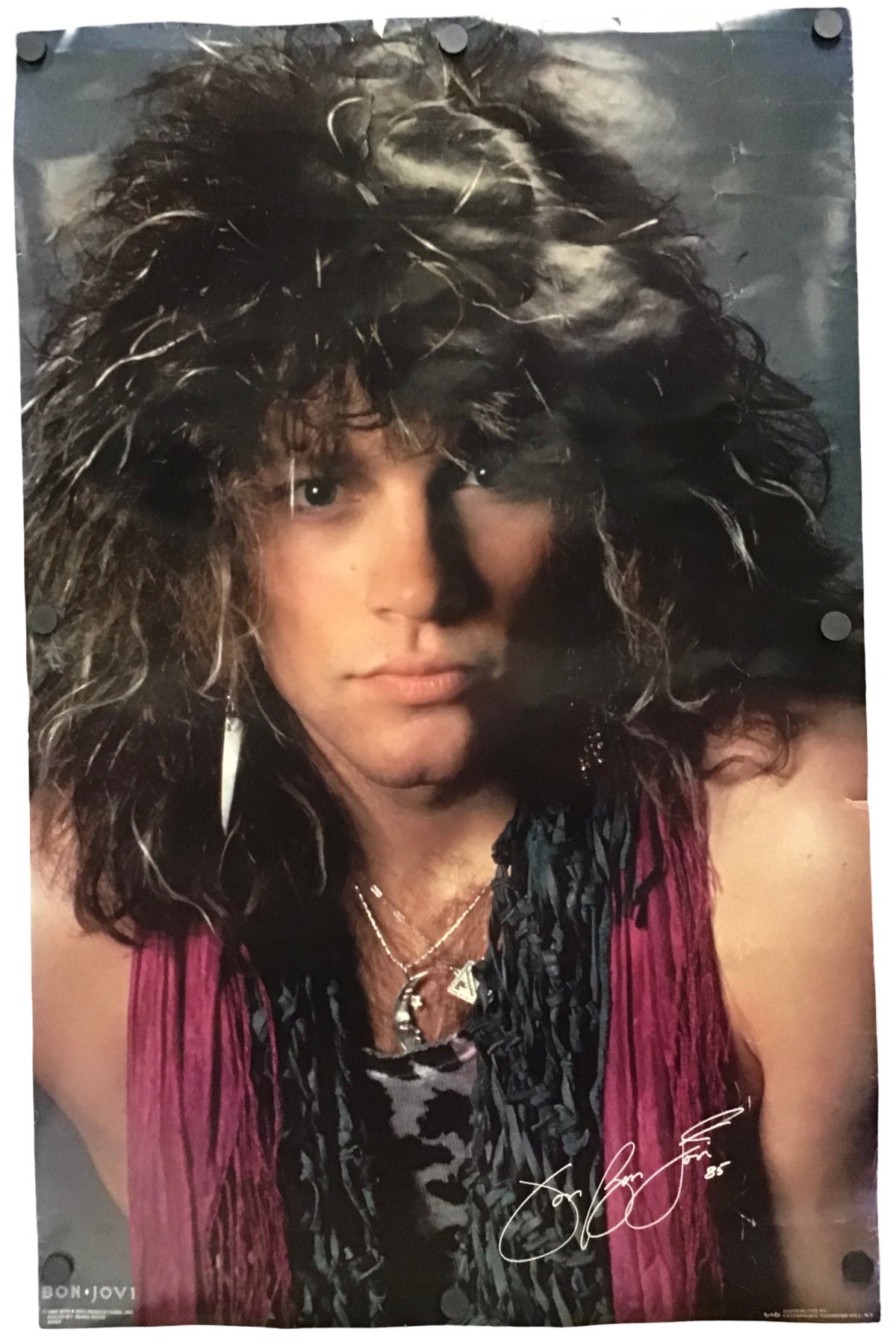A vertically oriented printed poster or photo print featuring a close-up portrait of a person with voluminous dark curly hair, wearing a dark top and magenta fringe scarf. The print is photographed hanging against a white background with visible metal hanging hardware at the corners.