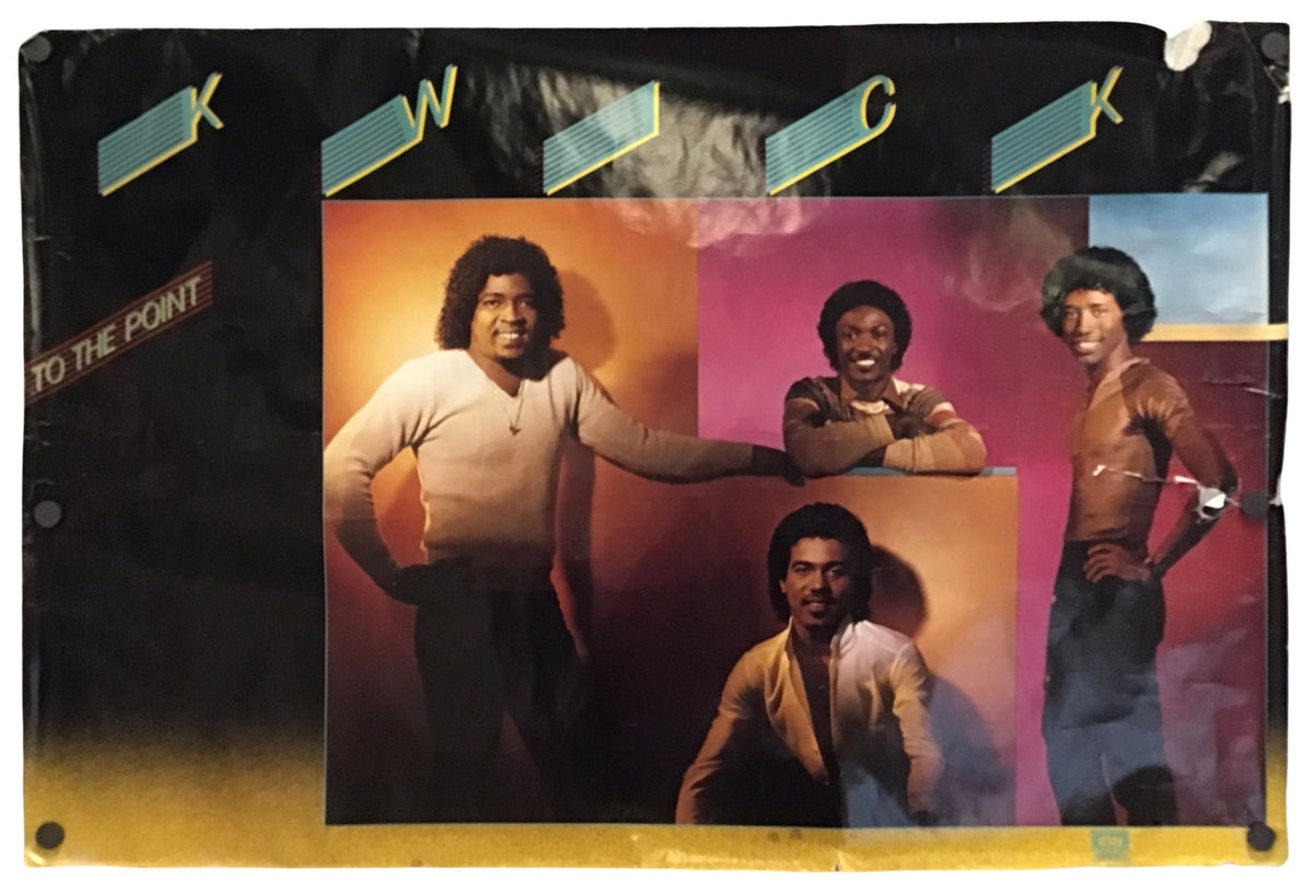 A vintage music poster for the band 'Kwick' featuring four members in front of a colorful orange, pink, and blue background, mounted on a black display board with gold lettering and a yellow bottom border.