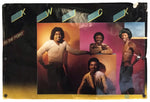 A vintage music poster for the band 'Kwick' featuring four members in front of a colorful orange, pink, and blue background, mounted on a black display board with gold lettering and a yellow bottom border.