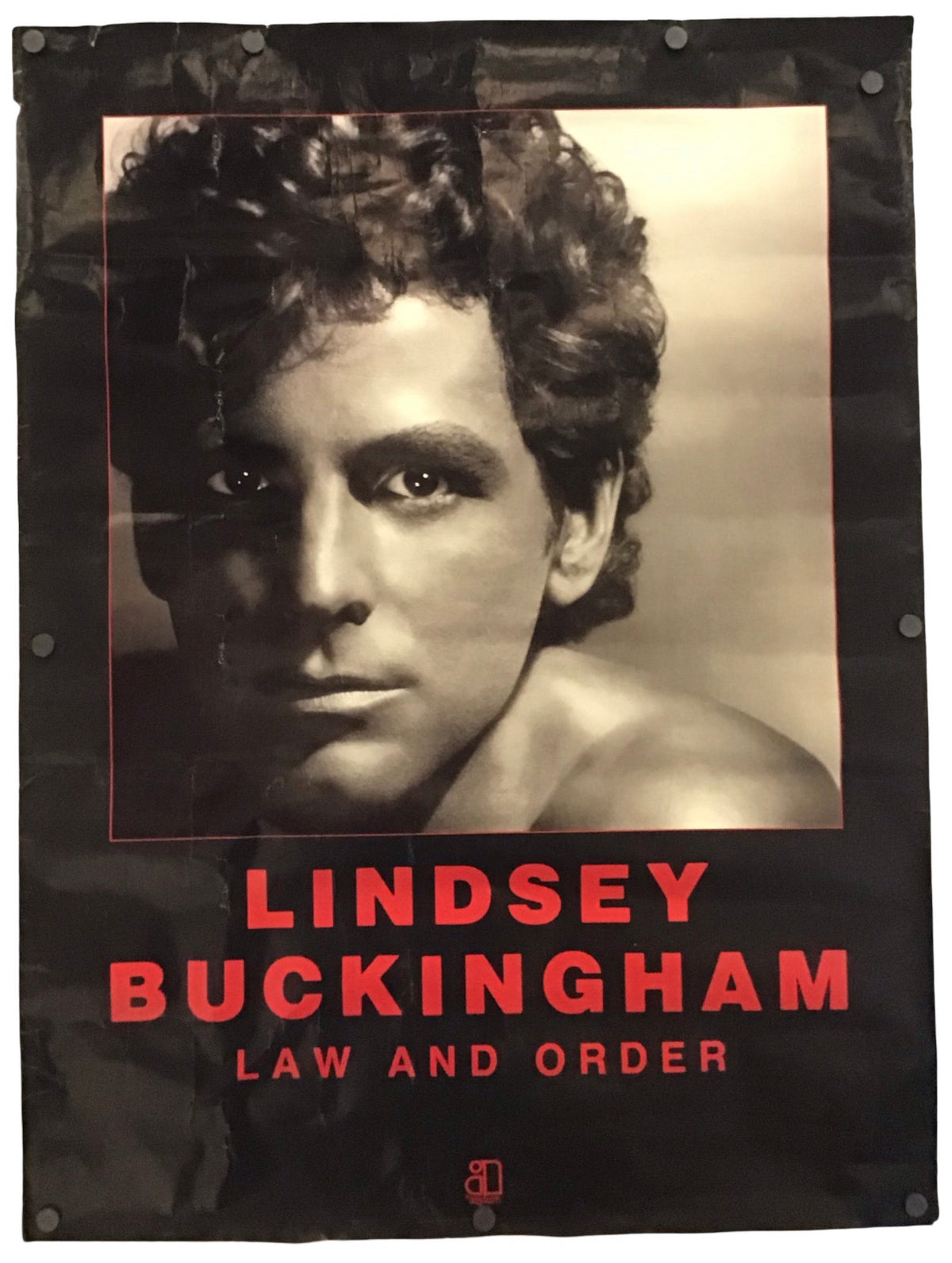 A vertical black banner or poster featuring a sepia-toned portrait of Lindsey Buckingham with the text 'LINDSEY BUCKINGHAM' and 'LAW AND ORDER' in red, photographed against a plain white background.