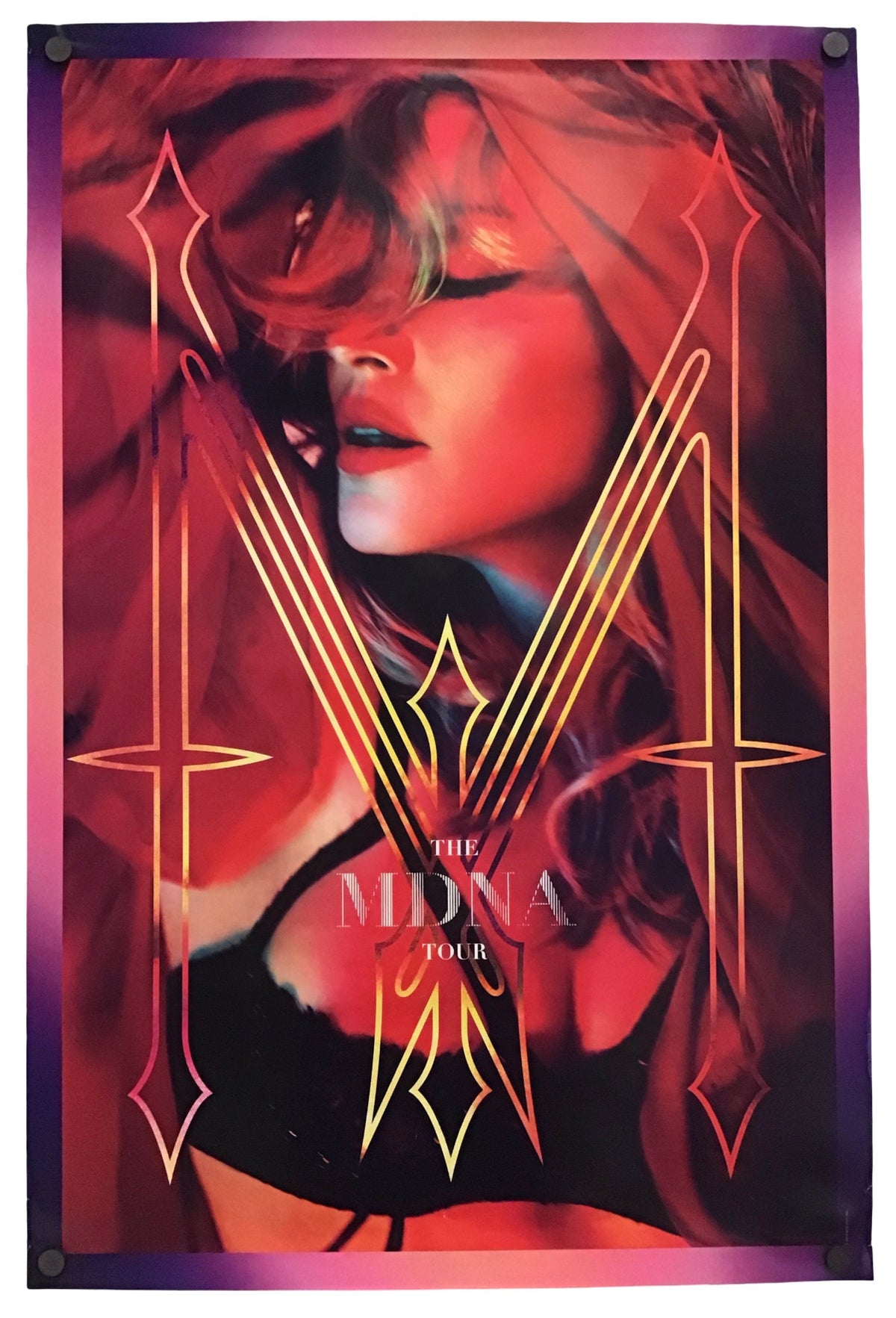 A vertical concert poster for 'The MDNA Tour' featuring a stylized portrait of a woman in red and pink tones with gold geometric line art and the text 'THE MDNA TOUR' near the bottom, displayed against a white background.