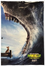 A vertical movie poster for 'Meg 2: The Trench' featuring a giant shark with open jaws above a small boat with a dog, set against a blue sky and ocean. The poster includes the movie title and release details at the bottom right.