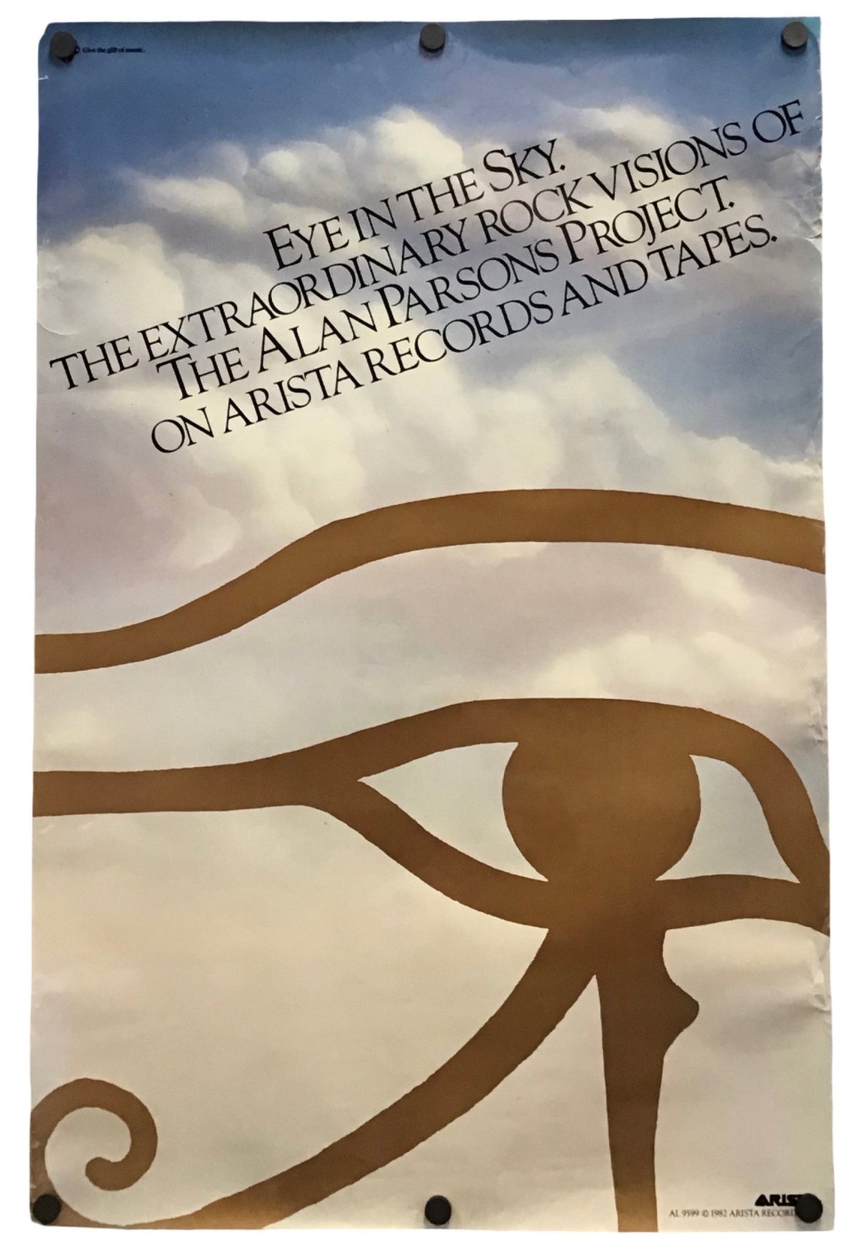 A vertical printed poster or banner featuring the text 'EYE IN THE SKY: THE EXTRAORDINARY ROCK VISIONS OF THE ALAN PARSON'S PROJECT ON ARISTA RECORDS AND TAPE' above a large brown eye motif over a cloudy sky background, shown hanging against a white wall.