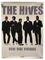 A vintage-style band poster for 'The Hives' featuring five men in black suits against a light background, with the text 'THE HIVES' at the top and 'VENI VIDI VICIOUS' at the bottom. The poster is shown hanging with visible wall fasteners.