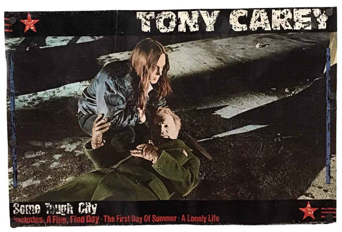 A rectangular printed cover or poster featuring the text 'TONY CAREY' at the top and 'Some Tough City' at the bottom, with a dark scene showing a woman kneeling beside a person on the ground. The item is photographed against a plain white background.