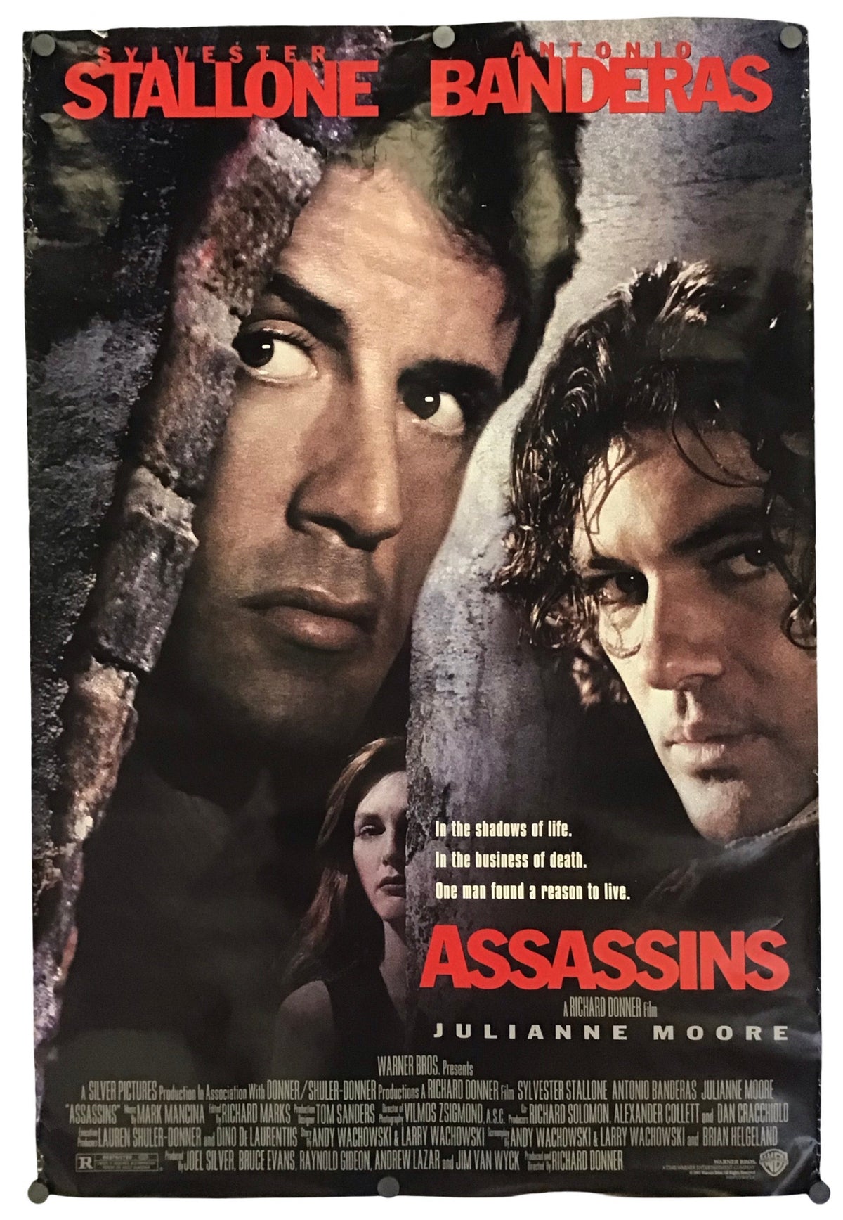 A vertical movie poster for the film 'Assassins' featuring close-up portraits of Sylvester Stallone and Antonio Banderas, with Julianne Moore at the bottom, red title text, and a dark textured background.