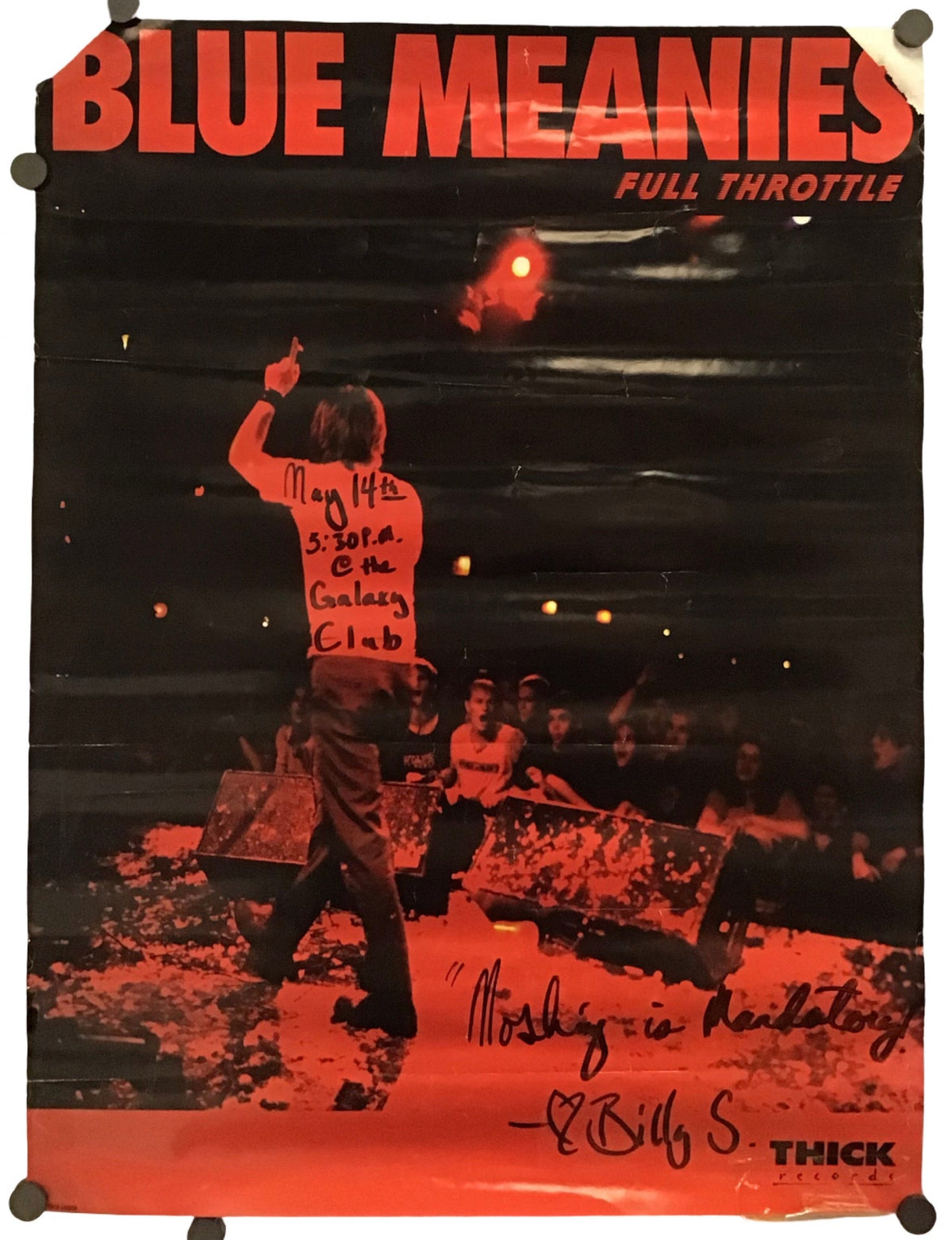 A vintage-style poster for the band Blue Meanies, featuring a dark concert scene with a performer and bold orange-red title text at the top. The poster is photographed hanging against a white background with clips at the corners.