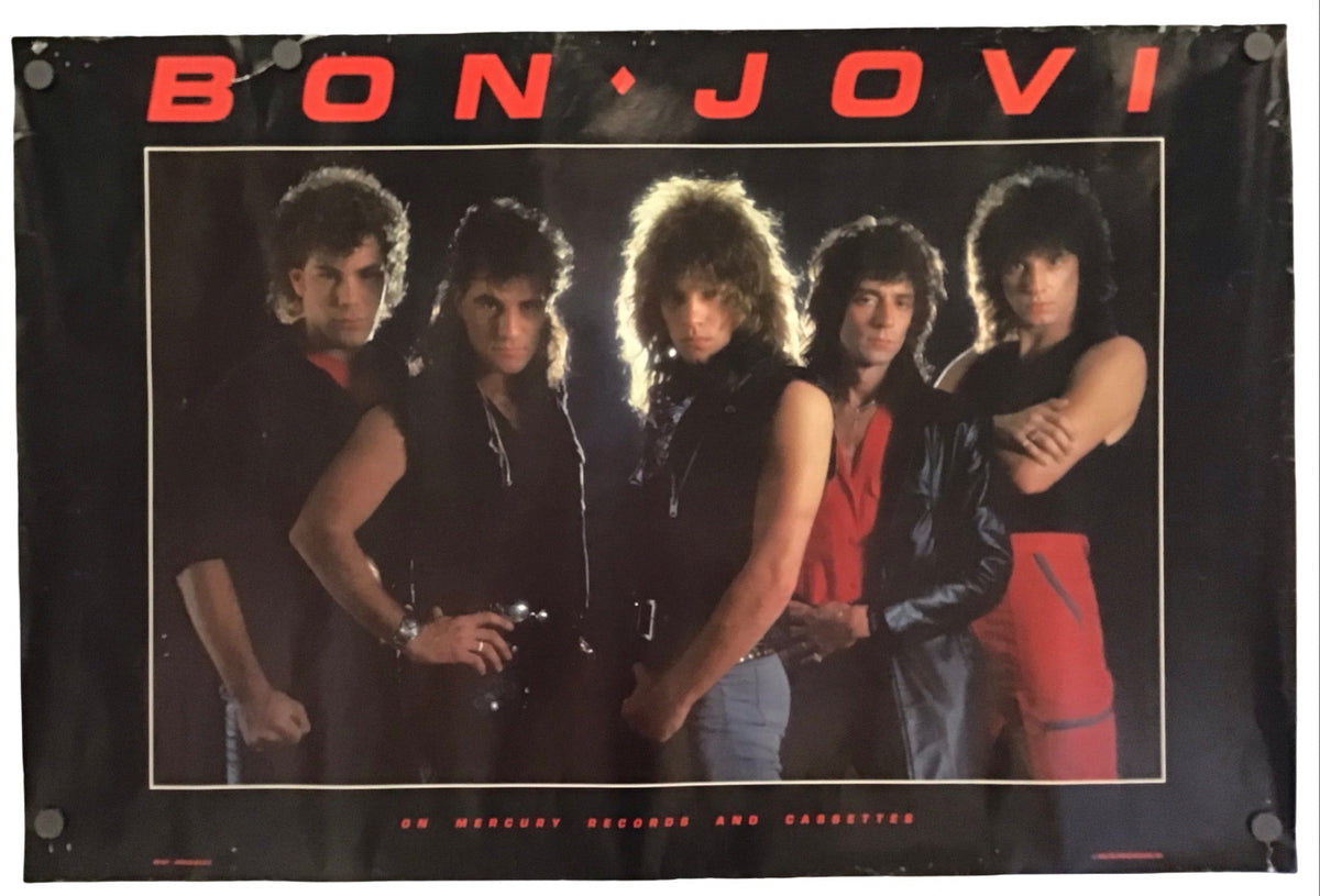 A vintage-style Bon Jovi band poster or banner hanging against a plain white background. The black poster features the band members in a central photo, with 'BON JOVI' in large red letters across the top and small red text at the bottom.