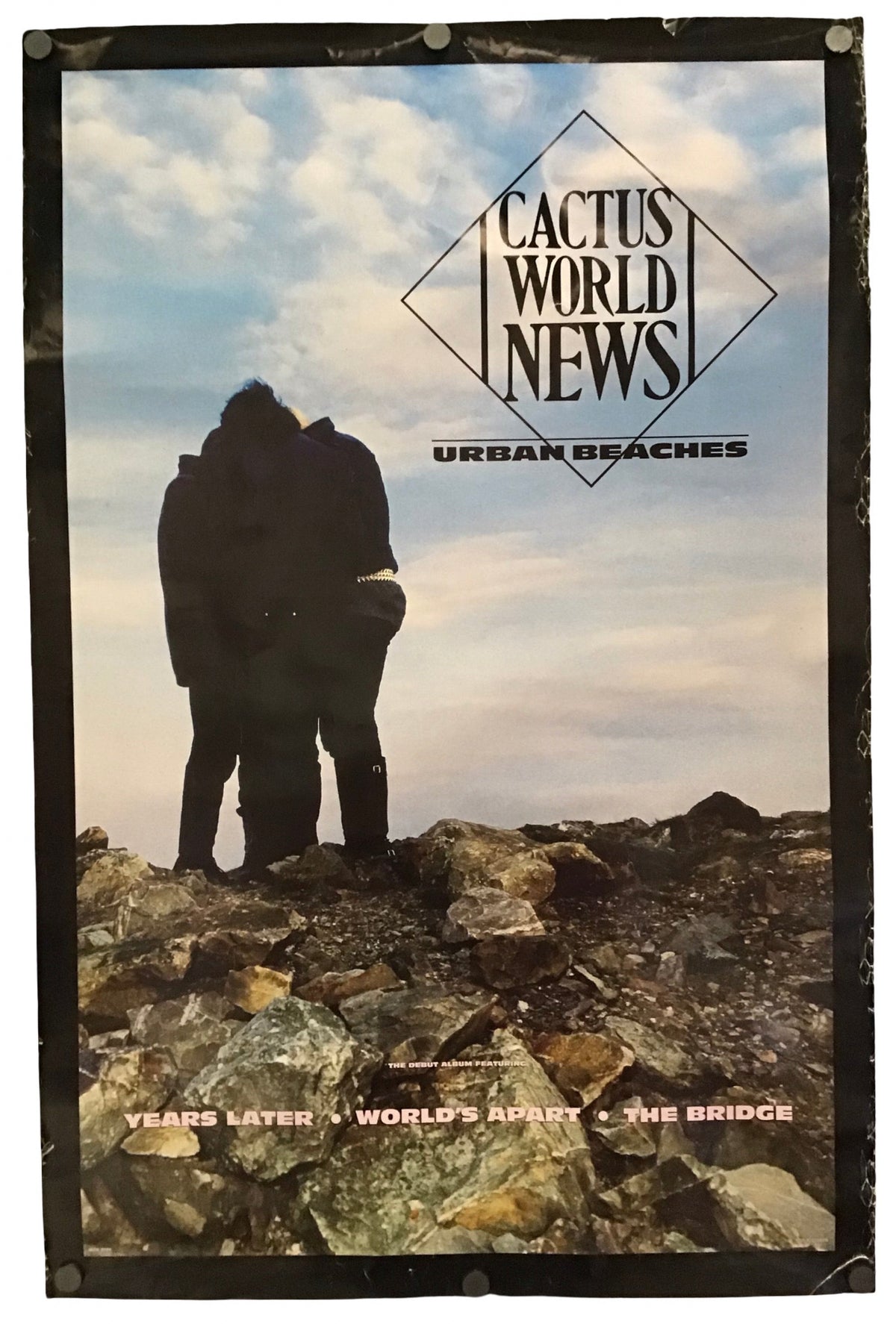 A vintage-style poster or print for Cactus World News featuring a silhouetted couple embracing on rocky ground under a cloudy sky, with the text 'Urban Beaches' and 'Years Later / World's Apart / The Bridge'.