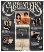 A vintage Carpenters music poster displayed flat against a white background. The poster features the band's name in large metallic-style lettering at the top, several black-and-white and color photos of the band members, and a central album cover insert for 'Carpenters' with text reading 'Saturday Night Moves'.