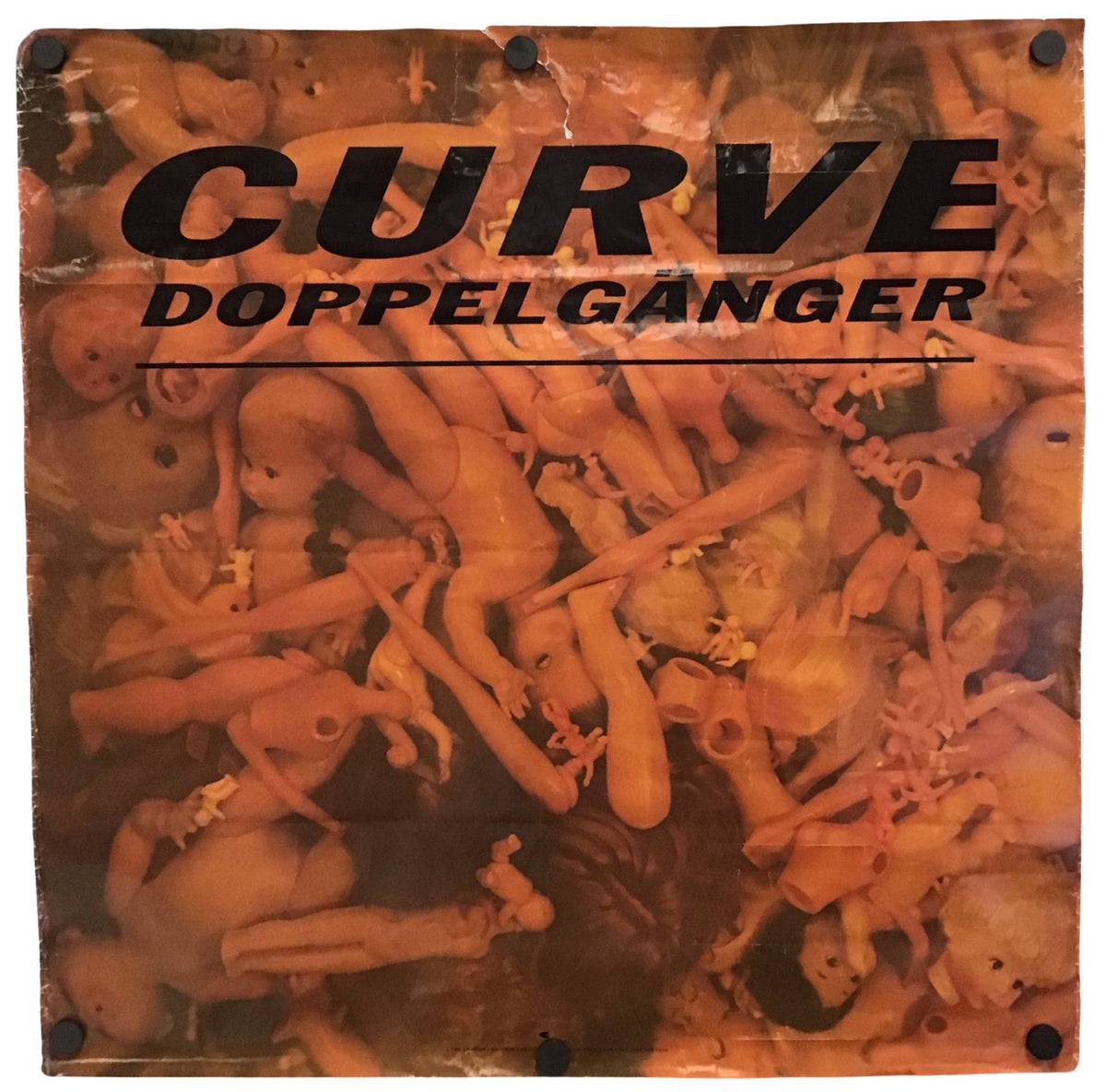 A square printed banner or sign with black metal grommets at the corners, featuring the text 'CURVE DOPPELGANGER' over a warm-toned photograph of many nude female bodies. The item is photographed against a plain white background.