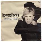 A square printed poster or album-cover style print featuring a black-and-white portrait of Howard Jones with the text 'howard jones' and 'one to one' on a warm off-white background, photographed against a white backdrop with visible mounting clips at the corners.