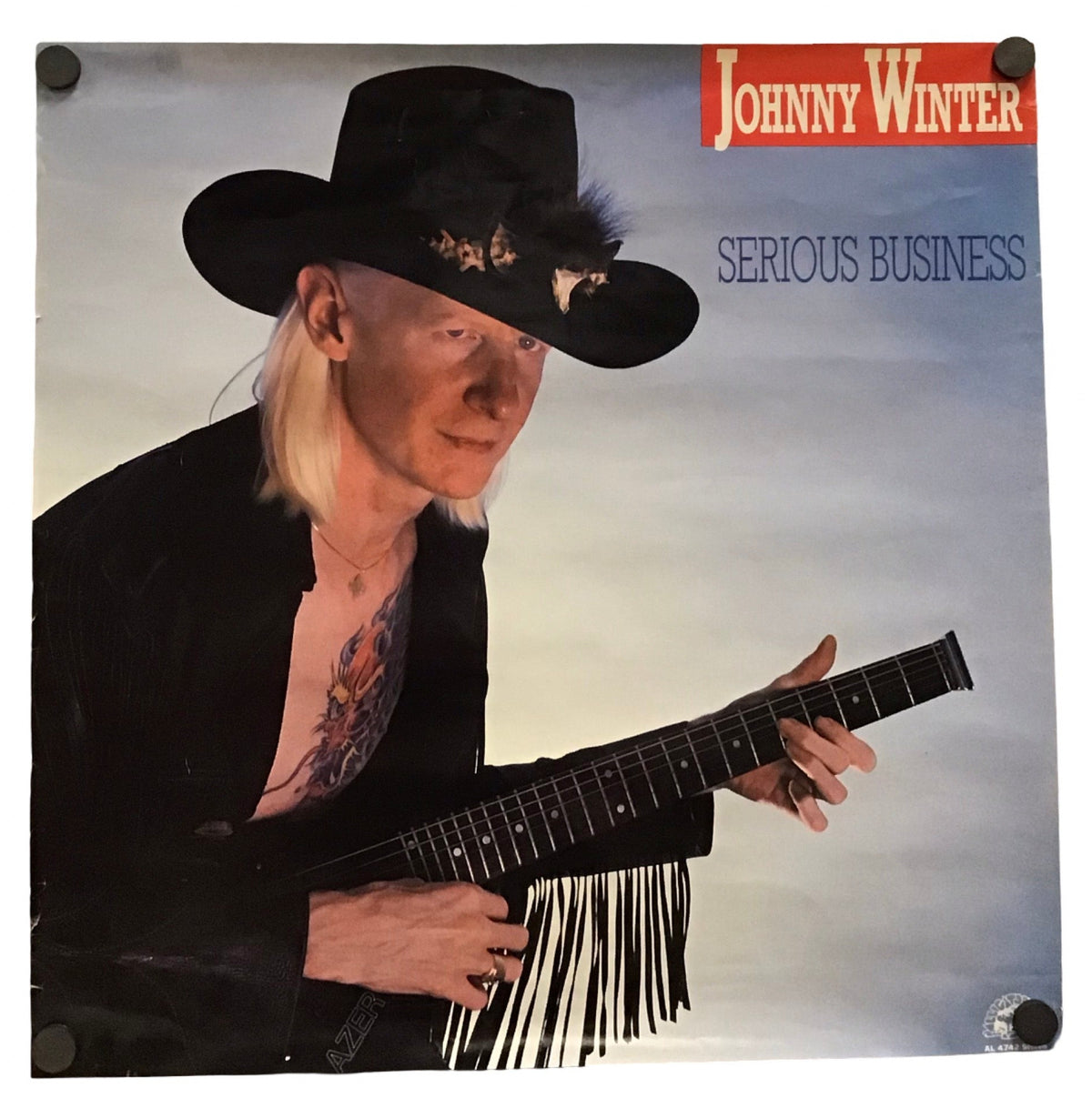 Johnny Winter 'Serious Business' vinyl record album cover, featuring a photo of the artist in a black cowboy hat and black jacket holding a black guitar against a pale sky background.
