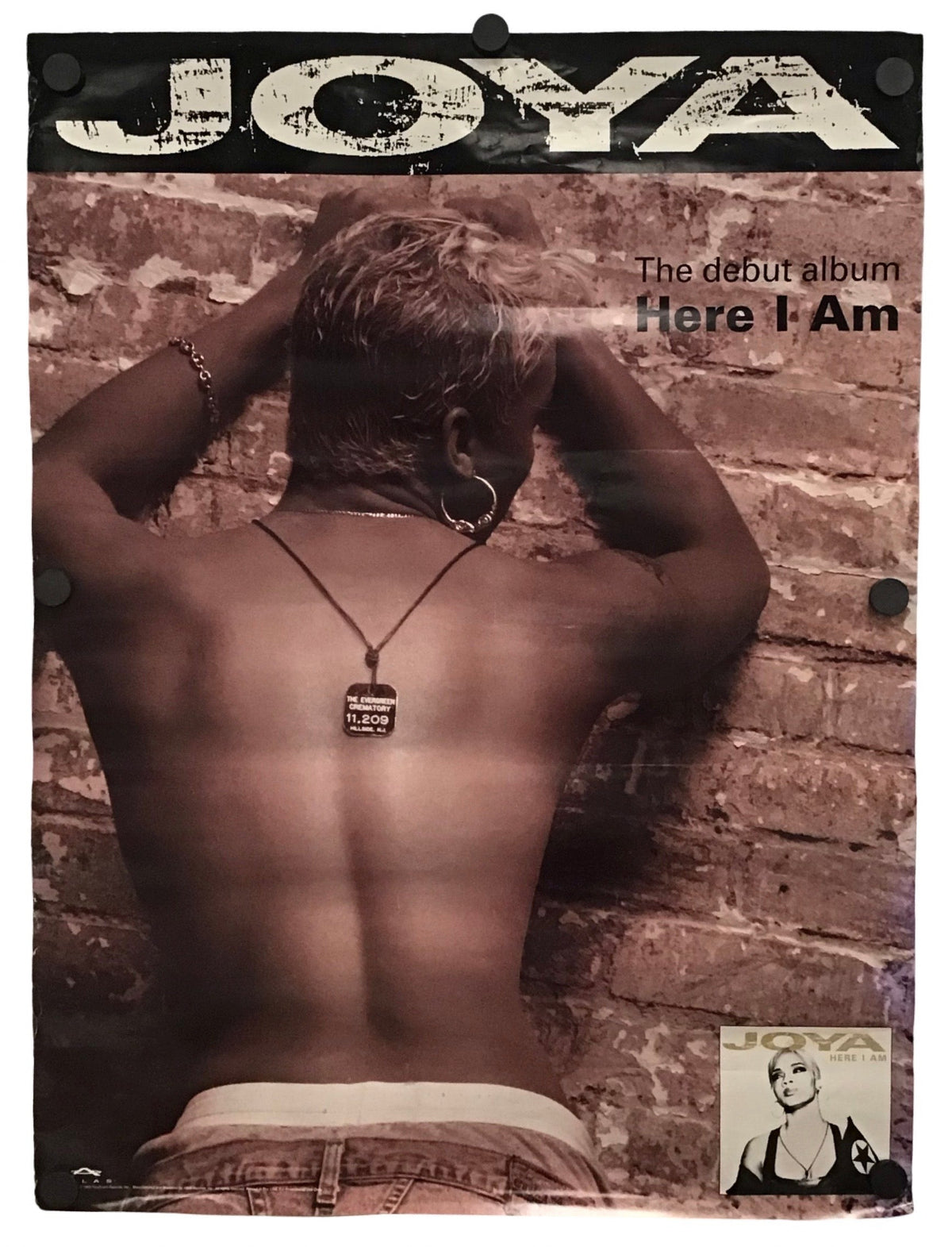 A rectangular poster or print featuring the album cover art for Joya's 'Here I Am', showing a shirtless person from behind against a brick wall, with the text 'JOYA' at the top and 'Here I Am' on the right.