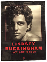 A vertical black banner or poster featuring a sepia-toned portrait of Lindsey Buckingham with the text 'LINDSEY BUCKINGHAM' and 'LAW AND ORDER' in red, photographed against a plain white background.