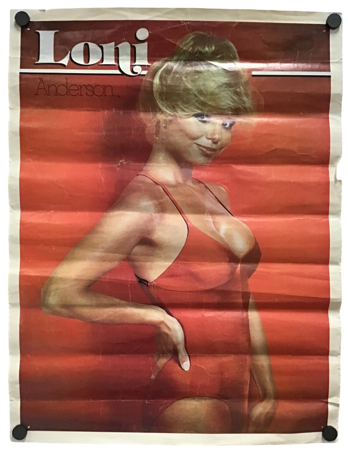 Vintage poster for 'Loni Anderson' featuring a woman in a red swimsuit against a red background, with the title 'Loni' in large white letters at the top. The poster is mounted with black clips at the corners on a white background.