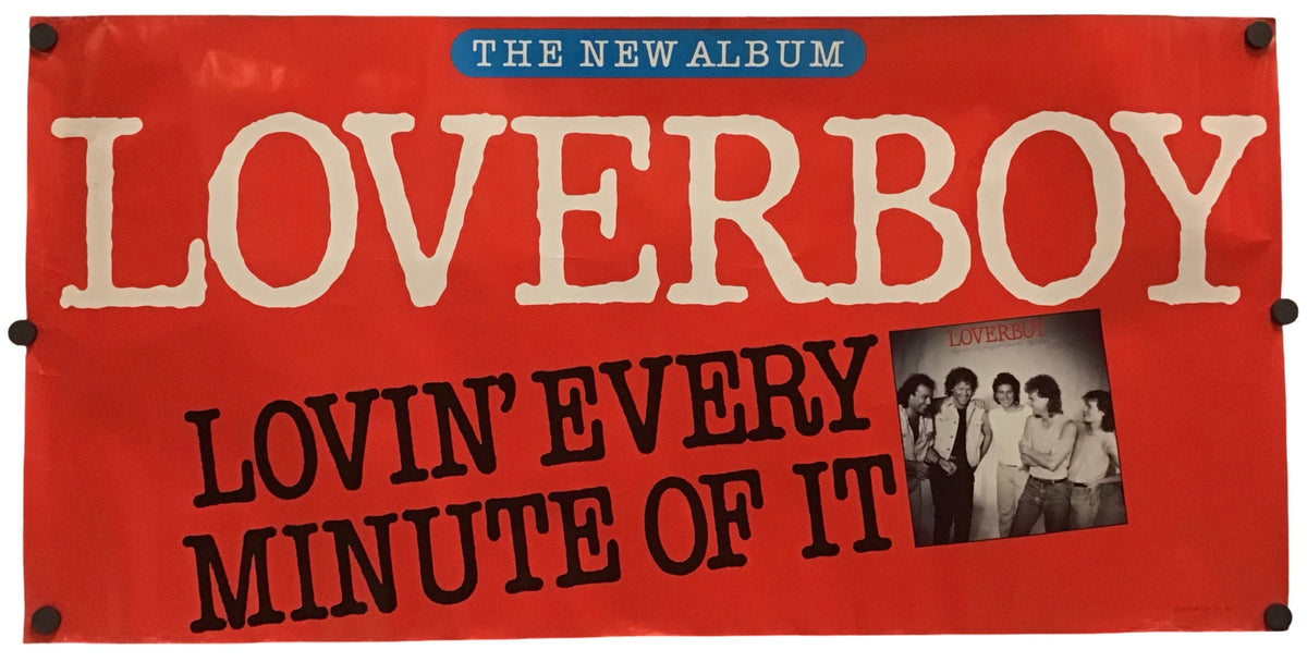 A red fabric banner featuring the text 'THE NEW ALBUM LOVERBOY LOVIN' EVERY MINUTE OF IT' in cream and black lettering, with a small black-and-white group photo on the right, shown against a plain white background.