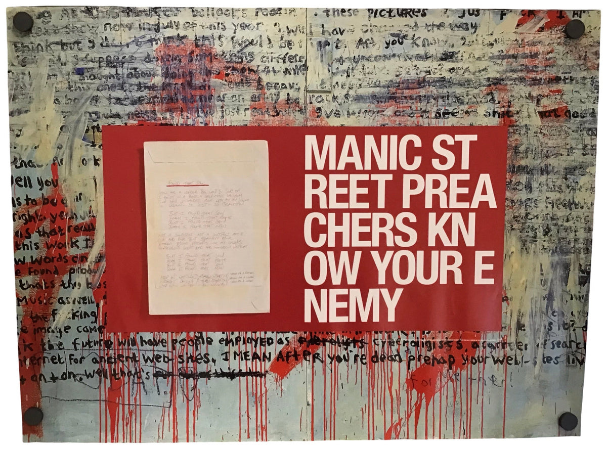 A square wall-mounted art print or poster featuring a red central panel with white text reading 'MANIC STREET PREACHERS KNOW YOUR ENEMY' over a distressed collage background with handwritten text and red paint drips.