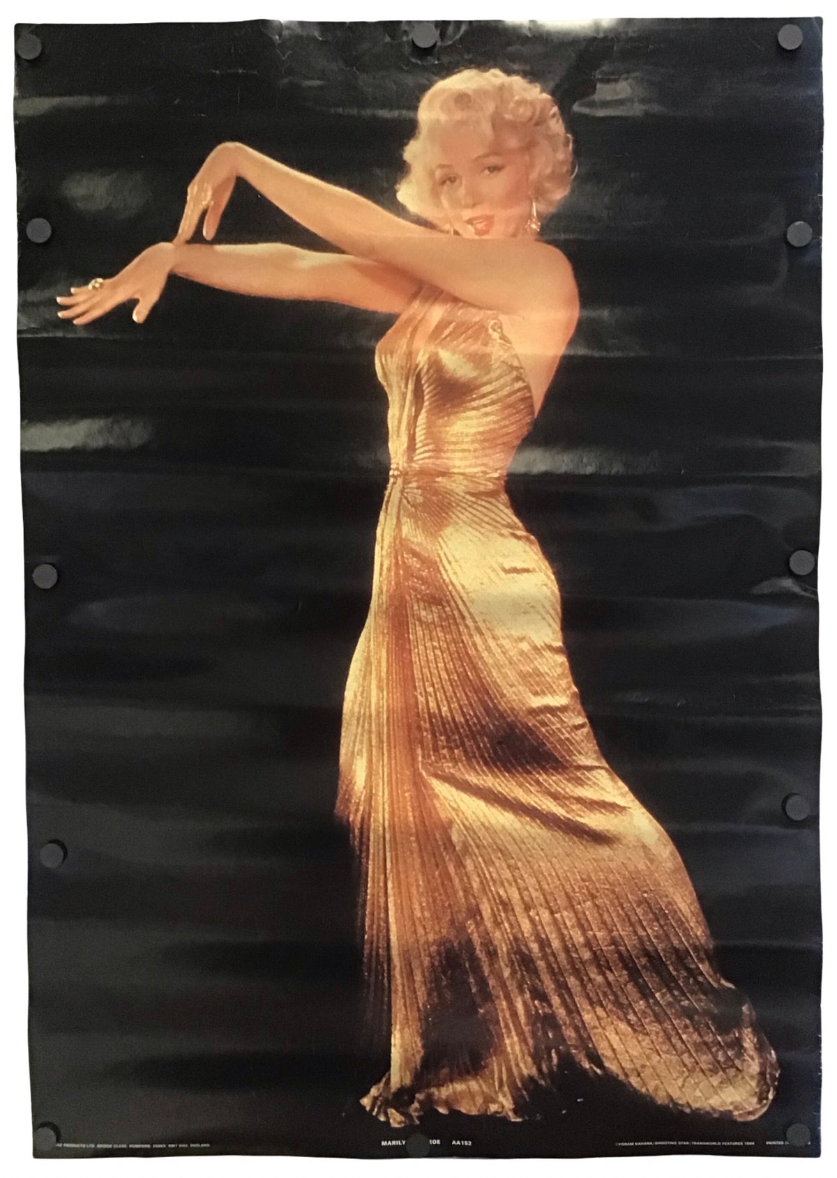 A vertical poster print featuring a stylized portrait of Marilyn Monroe in a shimmering gold dress against a dark black background, with visible mounting holes along the left and right edges.