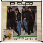 A vintage music poster for the band Player, titled 'Spies of Life', featuring a group photo of the four band members and album artwork in the bottom-left corner, displayed on a white background with black binder clips at the corners.