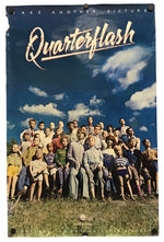 A vintage Quarterflash promo poster featuring a group posing outdoors under a blue sky with clouds, with the title 'Quarterflash' in large white script at the top.