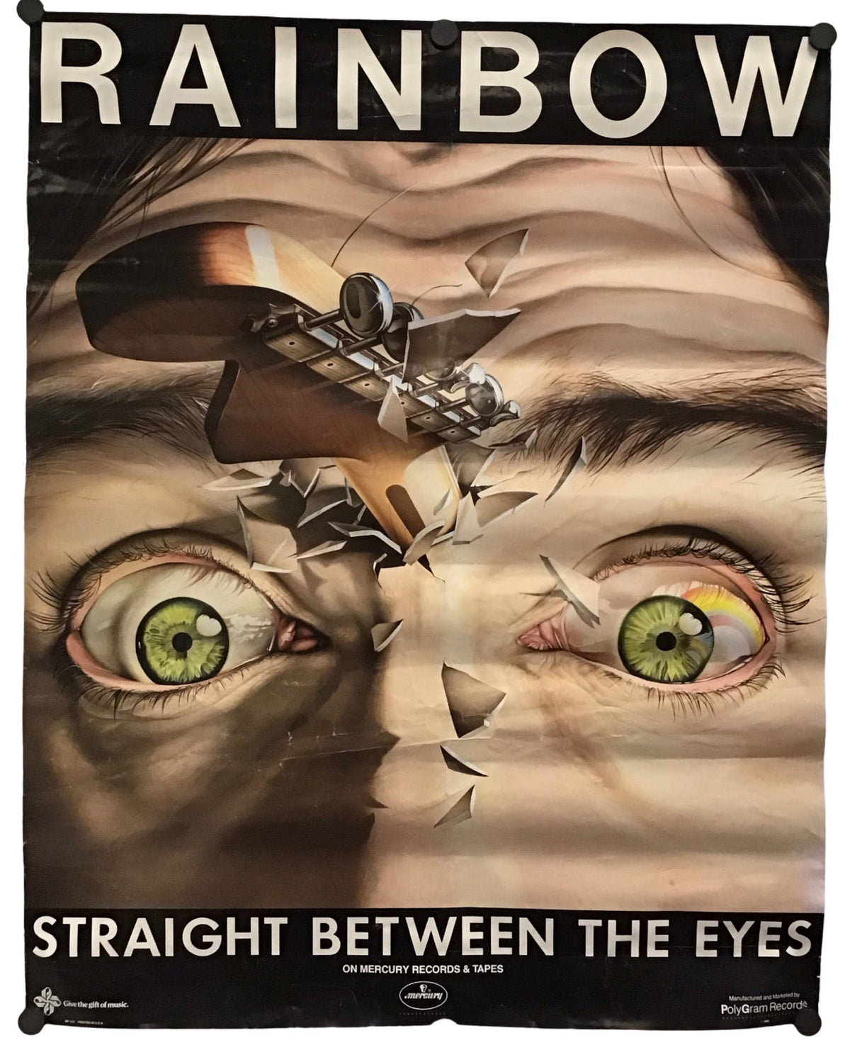 A poster print featuring a surreal close-up of a face with green eyes, broken shards, and a small airplane, with the text 'RAINBOW' at the top and 'STRAIGHT BETWEEN THE EYES' at the bottom.
