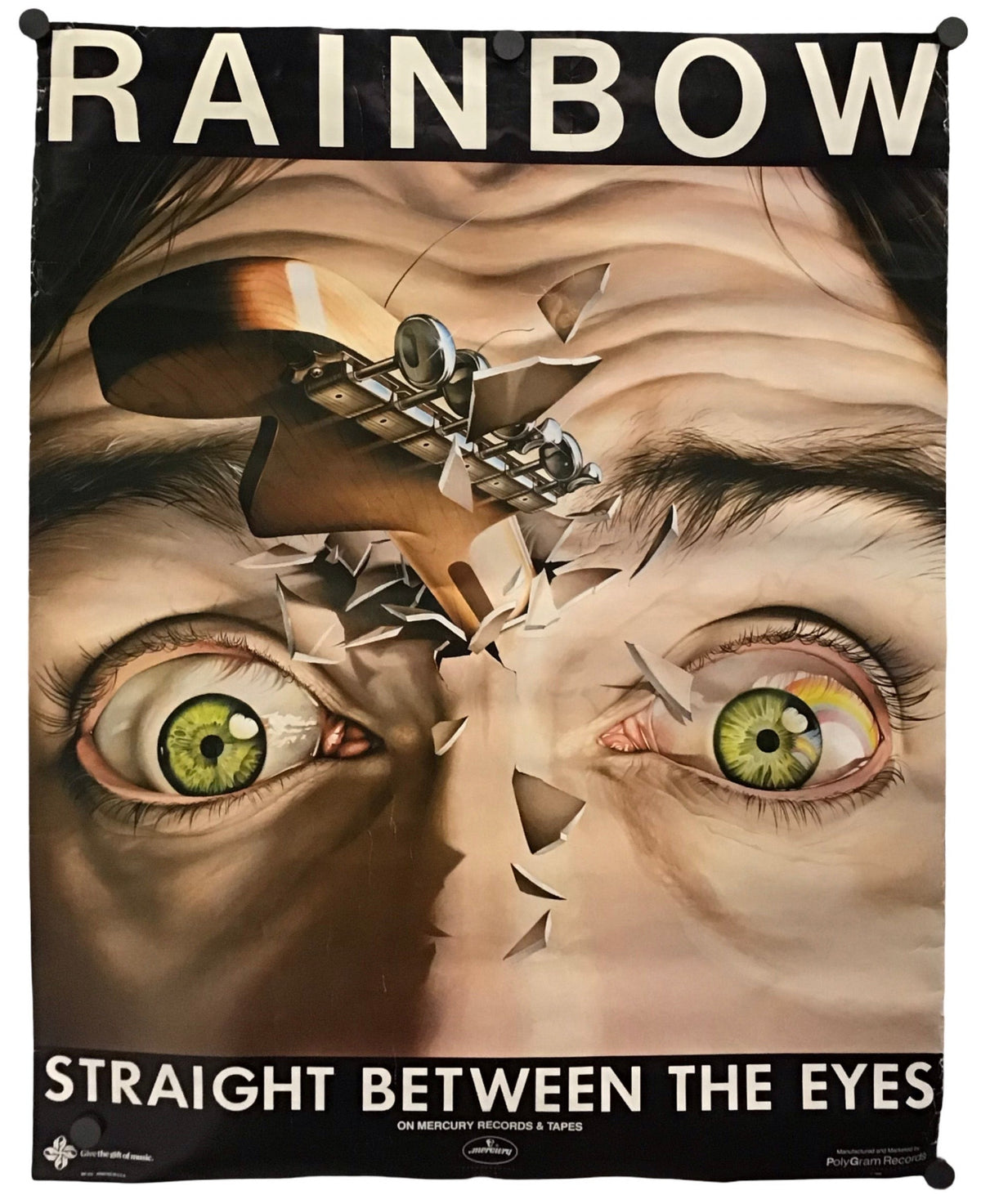 A poster print featuring a surreal close-up of a face with green eyes and a broken skull across the bridge, with the text 'RAINBOW' at the top and 'STRAIGHT BETWEEN THE EYES' at the bottom.