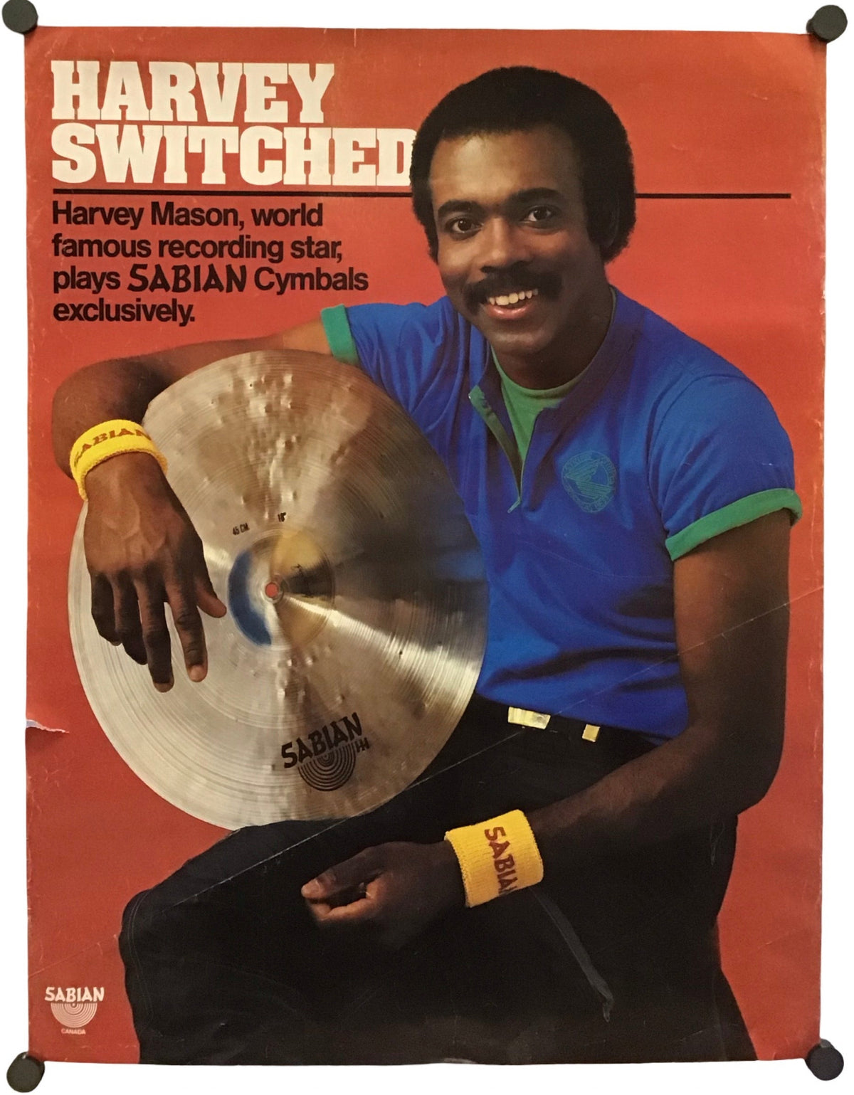 A vintage promotional poster for Sabian Cymbals featuring performer Harvey Mason, with the headline 'Harvey Switched' on a rust-orange background. The poster shows a seated man in a blue shirt holding a cymbal, and the Sabian logo appears at the bottom left.