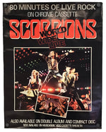 A vintage Scorpions 'World Wide Live' chrome cassette album poster, featuring the band performing live on stage with a small inset of the album cover, set against a black background.