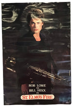 A vintage movie poster for the film 'St. Elmo's Fire' featuring Rob Lowe as Bill Hixx, shown hanging against a white wall.