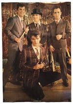 A vintage band poster featuring four men in suits posed against a gold tinsel backdrop, shown hanging on a white wall.