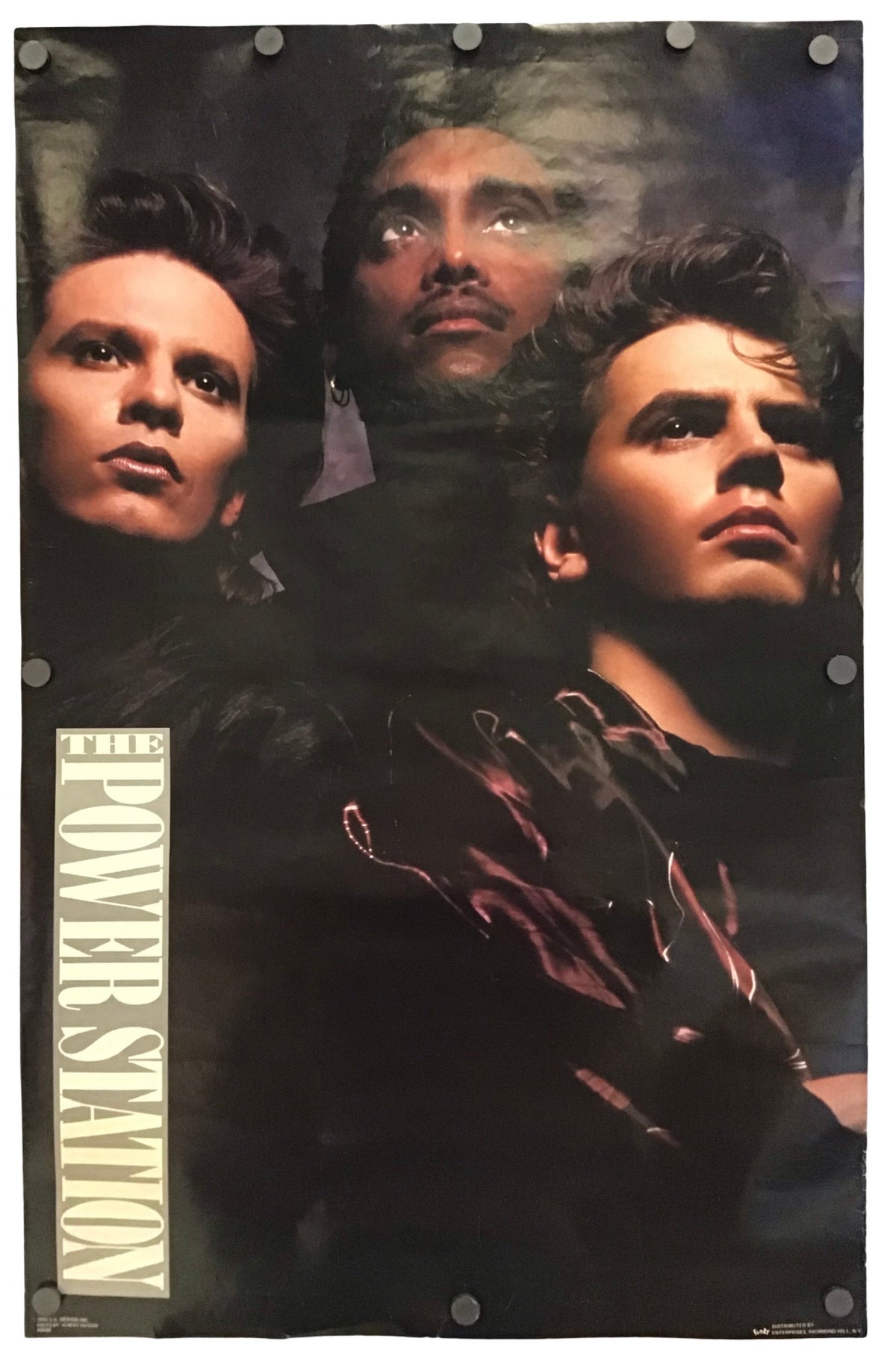 A vintage-style band poster for Power Station, featuring three men in dark clothing against a smoky black background, with the text 'THE POWER STATION' printed vertically along the left side.