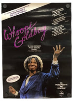 A vertical poster print for Whoopi Goldberg's film 'Goldberg' featuring a black background, pink script title, and a photo of Goldberg in a blue robe raising her hand. The poster includes critical quotes and is shown hanging against a white wall.